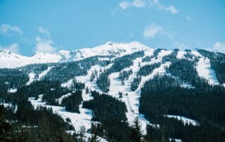 Snowy mountain ski resort with visible ski runs, chairlifts, and evergreen trees